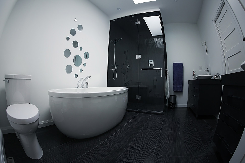 This is an example of a mid-sized contemporary master bathroom in Toronto with flat-panel cabinets, black cabinets, a freestanding tub, a corner shower, white walls, a two-piece toilet, porcelain floors, a vessel sink, mirror tile, black floor and a hinged shower door.