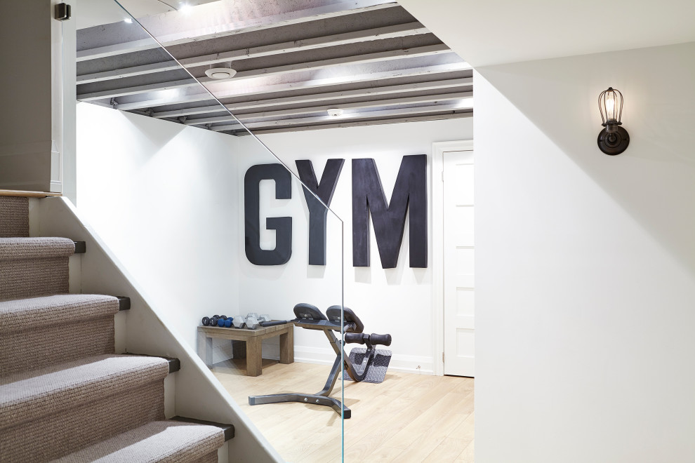 Small contemporary home gym in Toronto with white walls, laminate floors, white floor and exposed beam.