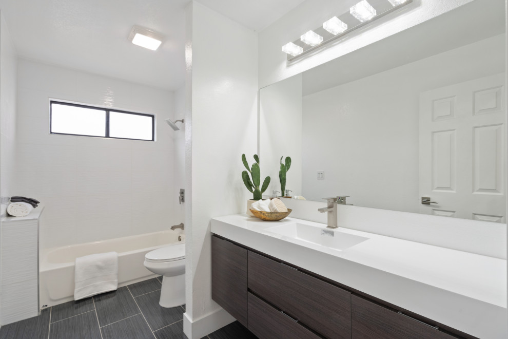 Idéer för stora funkis vitt en-suite badrum, med släta luckor, skåp i mörkt trä, ett badkar i en alkov, en dusch/badkar-kombination, en toalettstol med separat cisternkåpa, vit kakel, vita väggar, vinylgolv, ett integrerad handfat, bänkskiva i onyx och grått golv