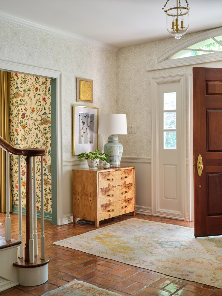 Aménagement d'une porte d'entrée classique avec un mur gris, tomettes au sol, une porte simple, une porte en bois brun et du papier peint.