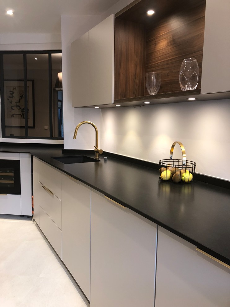 Photo of a mid-sized contemporary galley separate kitchen in Paris with an integrated sink, beaded inset cabinets, beige cabinets, granite benchtops, white splashback, ceramic floors, beige floor and black benchtop.