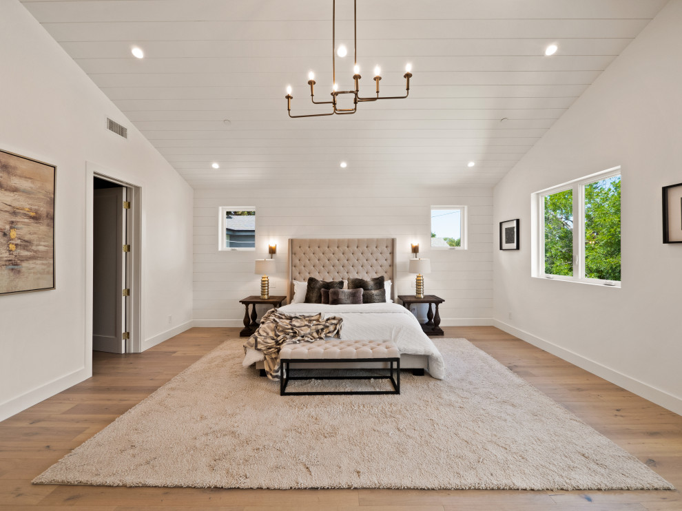 Design ideas for an expansive country master bedroom in Los Angeles with white walls, light hardwood floors, a standard fireplace, a plaster fireplace surround, vaulted and panelled walls.