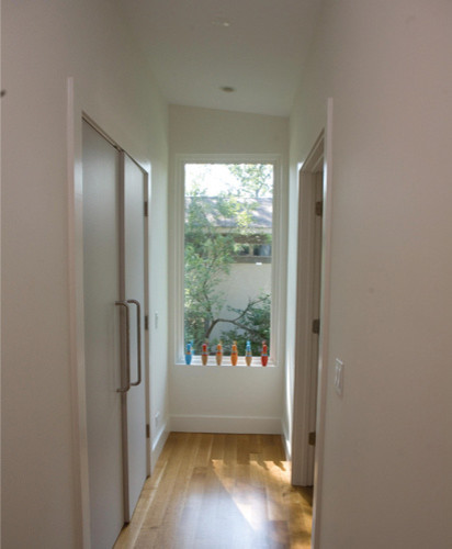 Photo of a small midcentury hallway in Chicago with white walls and light hardwood floors.