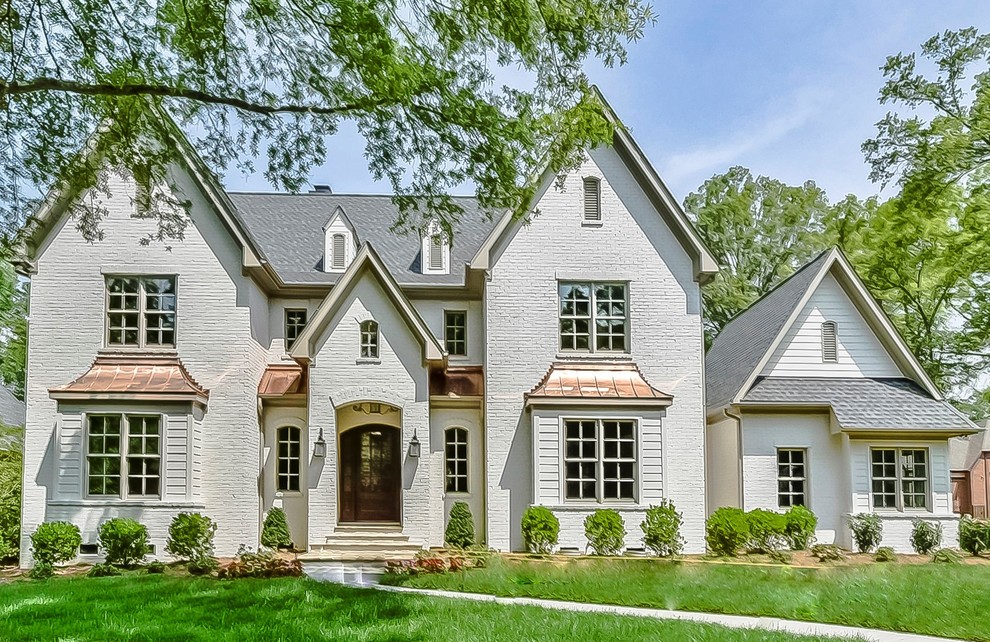 Photo of an expansive transitional two-storey brick white house exterior in Charlotte with a clipped gable roof and a mixed roof.