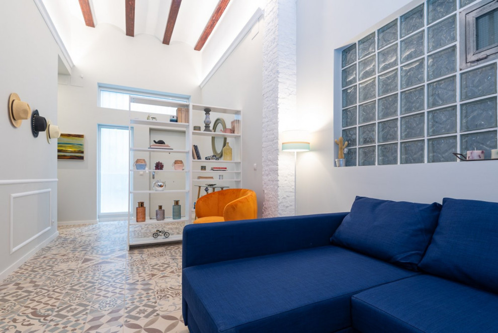 Immagine di un soggiorno classico di medie dimensioni e aperto con pareti bianche, pavimento con piastrelle in ceramica, TV a parete, pavimento multicolore e travi a vista