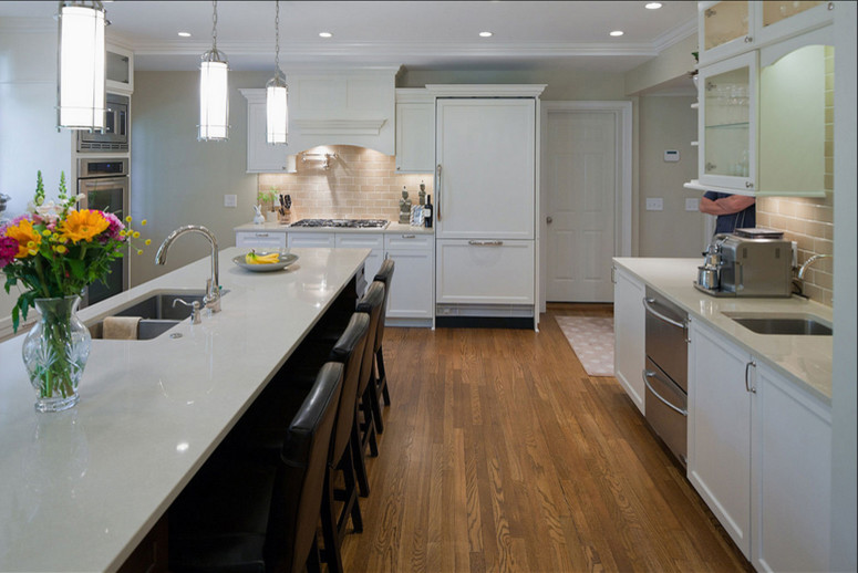 Inspiration for a transitional kitchen in Cleveland with an undermount sink, recessed-panel cabinets, quartzite benchtops, beige splashback, subway tile splashback, stainless steel appliances and light hardwood floors.