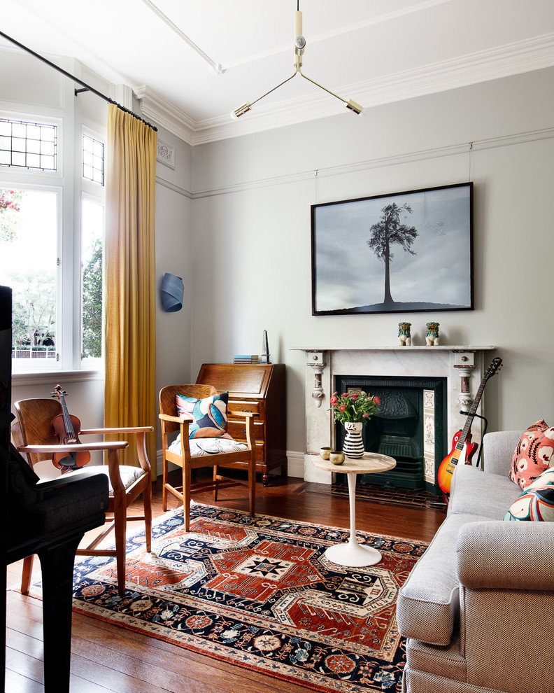 Photo of an eclectic living room in Sydney with grey walls, medium hardwood floors, a standard fireplace and brown floor.