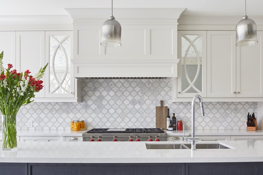 Enclosed kitchen - mid-sized transitional l-shaped light wood floor enclosed kitchen idea in Toronto with an undermount sink, shaker cabinets, white cabinets, granite countertops, white backsplash, cement tile backsplash, stainless steel appliances, an island and white countertops