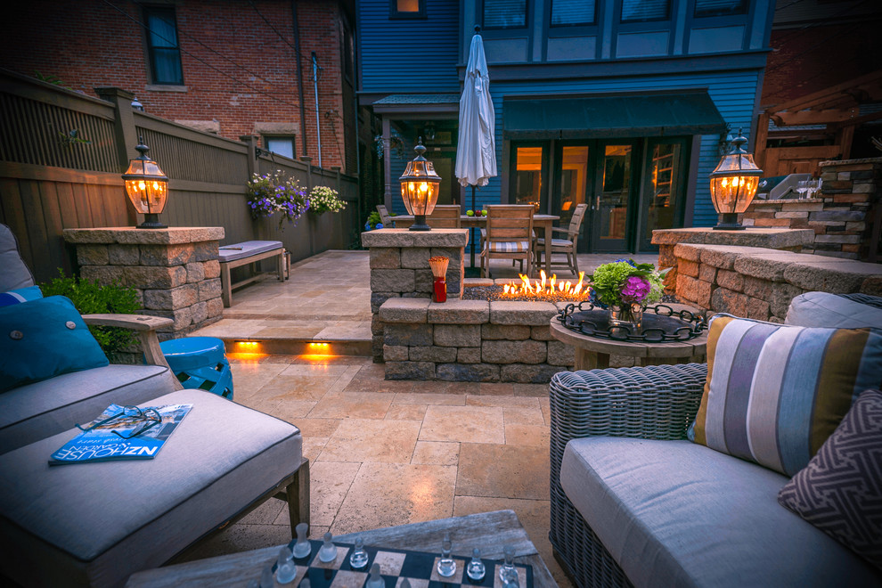 Inspiration for a small traditional backyard patio in Columbus with a fire feature, natural stone pavers and an awning.