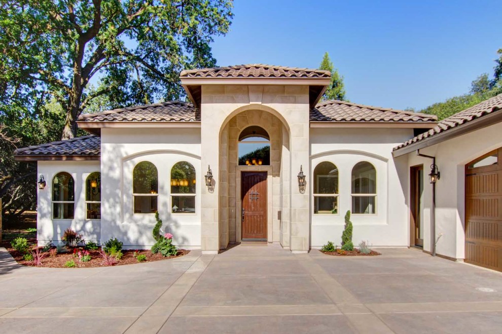 Inspiration for a mid-sized mediterranean one-storey stucco beige house exterior in Sacramento with a gable roof and a tile roof.