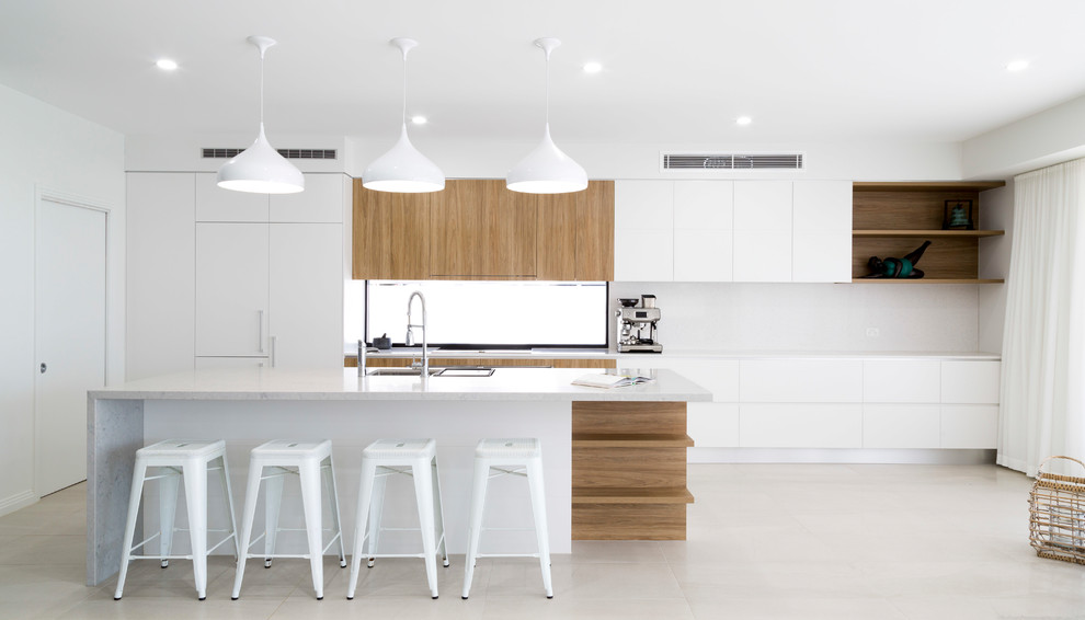 Design ideas for a contemporary galley kitchen in Gold Coast - Tweed with an undermount sink, flat-panel cabinets, white cabinets, white splashback, panelled appliances, with island, beige floor and white benchtop.