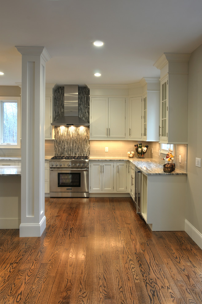 Inspiration for a large contemporary l-shaped kitchen in Boston with an undermount sink, beaded inset cabinets, white cabinets, quartzite benchtops, grey splashback, glass tile splashback, stainless steel appliances, medium hardwood floors, with island and brown floor.