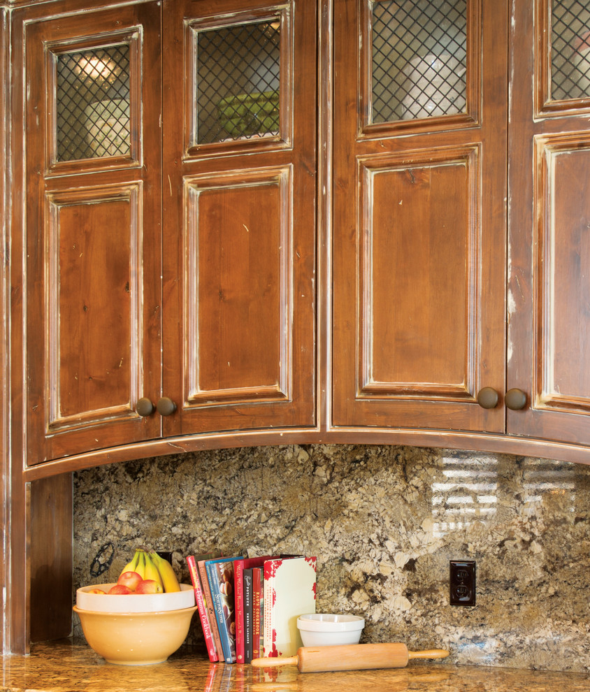 Large mountain style l-shaped dark wood floor open concept kitchen photo with recessed-panel cabinets, medium tone wood cabinets, stone slab backsplash, stainless steel appliances and an island