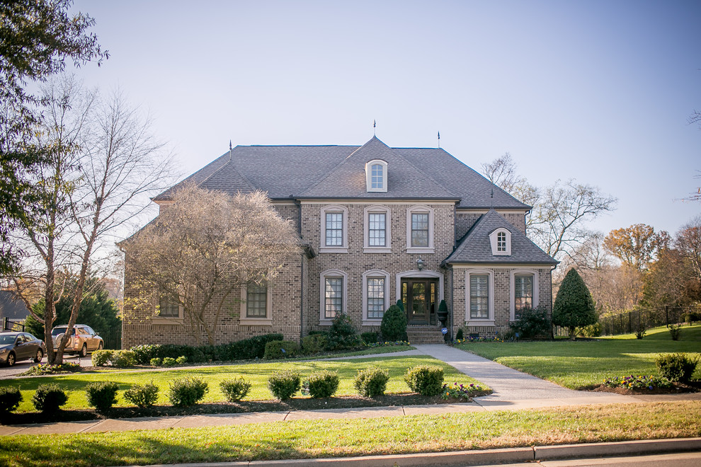 Photo of a traditional two-storey brick brown house exterior in Nashville with a hip roof and a shingle roof.