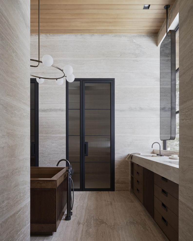 Idéer för ett mycket stort modernt beige en-suite badrum, med luckor med infälld panel, ett fristående badkar, en kantlös dusch, en vägghängd toalettstol, beige kakel, travertinkakel, beige väggar, travertin golv, ett integrerad handfat, beiget golv och dusch med gångjärnsdörr