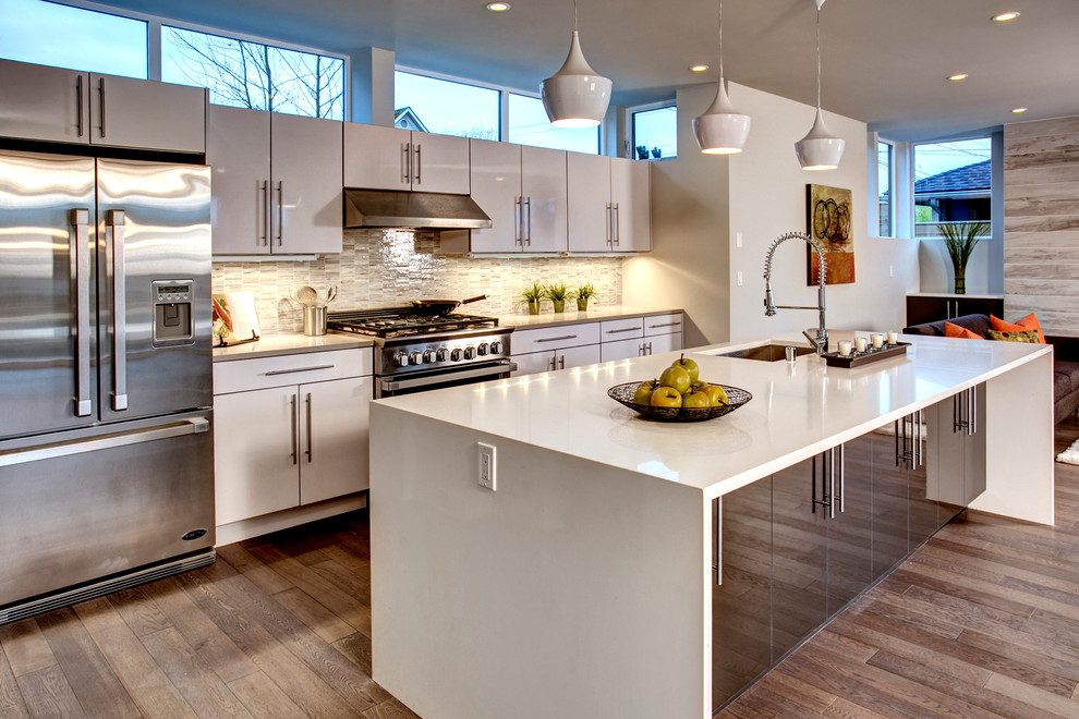Mid-sized contemporary galley open plan kitchen in Seattle with an undermount sink, flat-panel cabinets, white cabinets, multi-coloured splashback, stainless steel appliances, medium hardwood floors and with island.