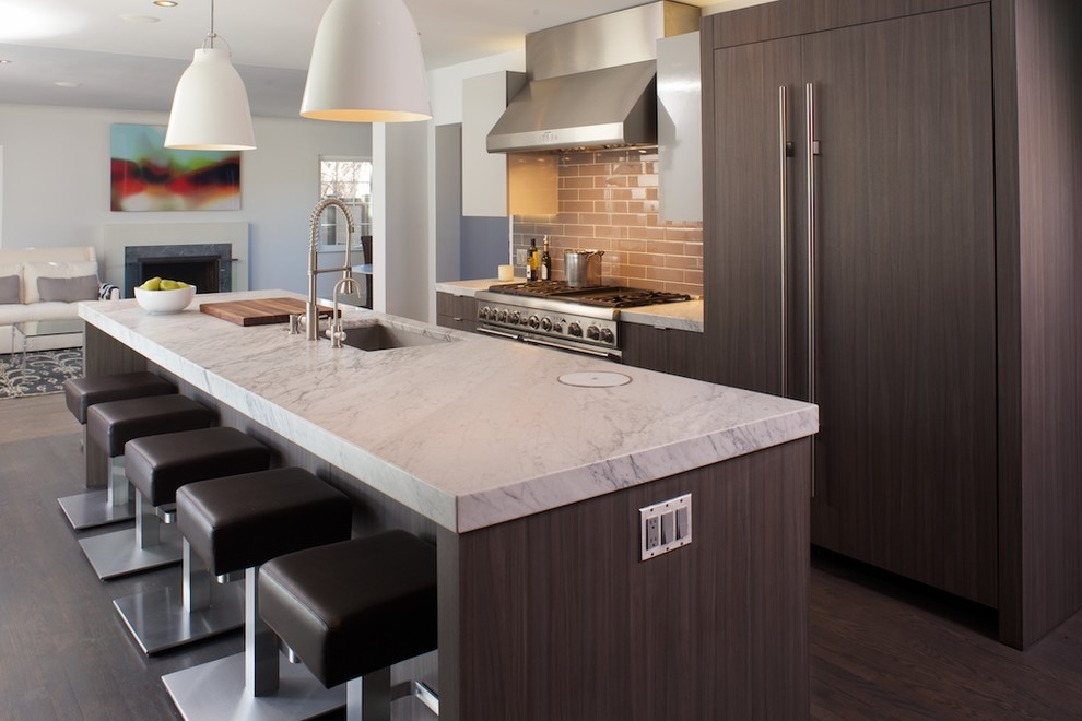 Example of a transitional galley dark wood floor open concept kitchen design in Denver with flat-panel cabinets, brown cabinets, marble countertops, glass tile backsplash, paneled appliances and an island
