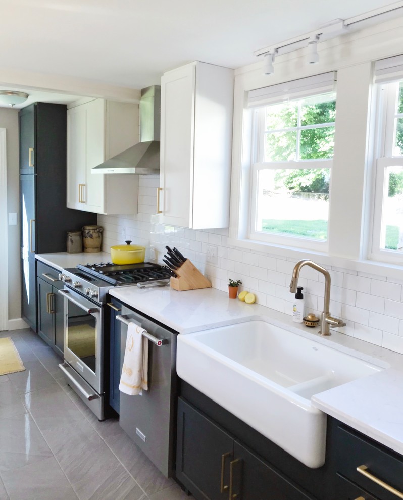 Example of a transitional gray floor kitchen design with a farmhouse sink, quartz countertops and stainless steel appliances