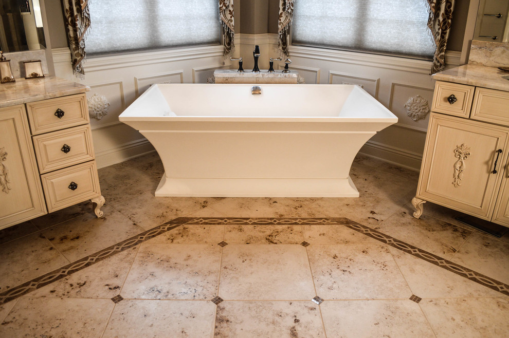 Photo of a large traditional master bathroom in Cleveland with furniture-like cabinets, white cabinets, a freestanding tub, an alcove shower, a two-piece toilet, multi-coloured tile, porcelain tile, grey walls, porcelain floors, an undermount sink and marble benchtops.