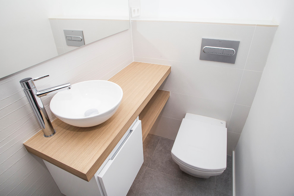 Aseo?[Foto de aseo With puertas de armario blancas, sanitario de una pieza, baldosas y/o azulejos blancos, paredes blancas, lavabo sobreencimera, encimera de madera, suelo gris and encimeras marrones ]:[Foto de aseos With puertas de armario blancas, sanitario de una pieza, baldosas y/o azulejos blancos, paredes blancas, lavabo sobreencimera, encimera de madera, suelo gris and encimeras marrones ]