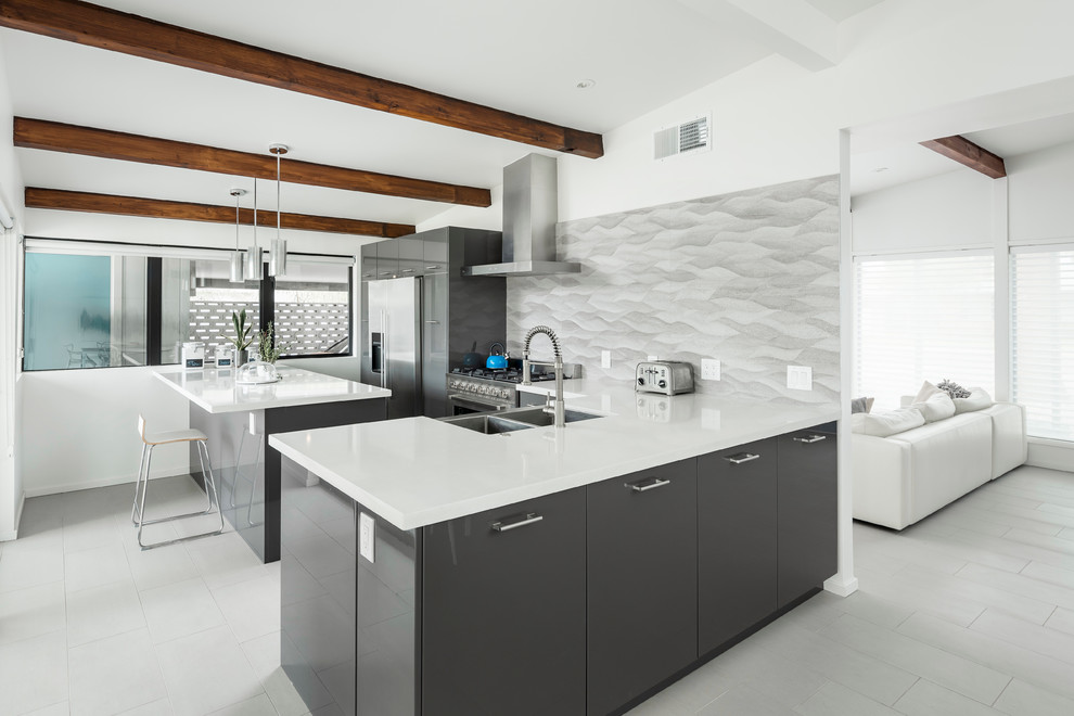 This is an example of a midcentury l-shaped open plan kitchen in Phoenix with a farmhouse sink, flat-panel cabinets, grey cabinets, quartz benchtops, grey splashback, porcelain splashback, stainless steel appliances, porcelain floors and with island.