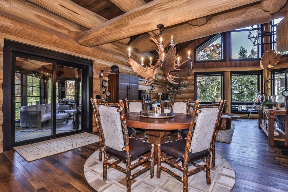 Example of a mountain style dark wood floor, brown floor, exposed beam and wood wall great room design with brown walls