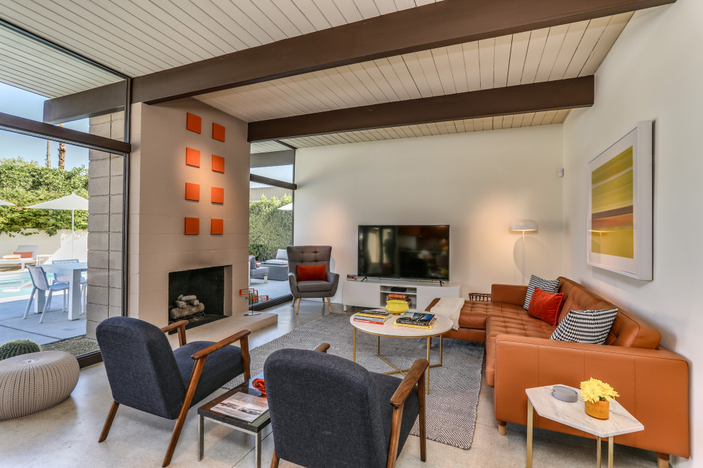 This is an example of a midcentury open concept living room in Other with white walls, concrete floors, a standard fireplace, a freestanding tv, beige floor, exposed beam and timber.