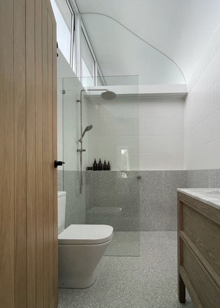 This is an example of a small contemporary master bathroom in Sydney with beaded inset cabinets, a double shower, a one-piece toilet, white tile, ceramic tile, terrazzo floors, an undermount sink, marble benchtops, grey floor, an open shower, grey benchtops, a niche, a single vanity and a freestanding vanity.