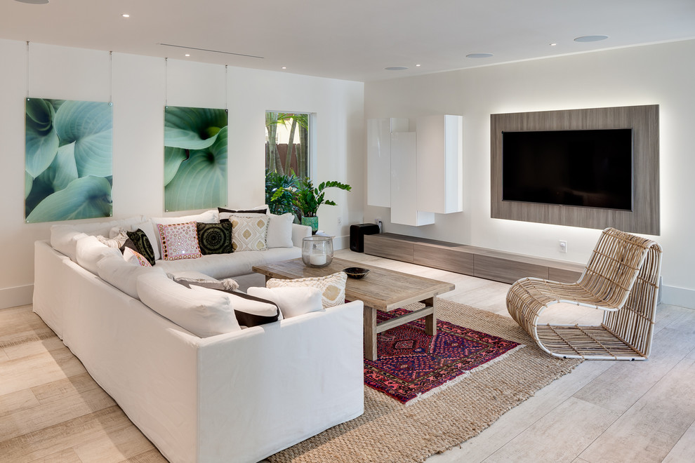 Photo of a contemporary family room in Miami with white walls, light hardwood floors, a wall-mounted tv and beige floor.