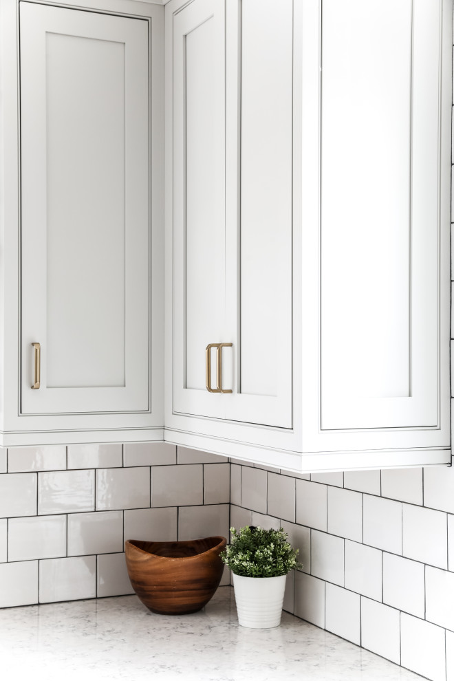 Eat-in kitchen - transitional l-shaped medium tone wood floor and brown floor eat-in kitchen idea in Boston with a farmhouse sink, beaded inset cabinets, white cabinets, quartz countertops, white backsplash, subway tile backsplash, stainless steel appliances, an island and gray countertops