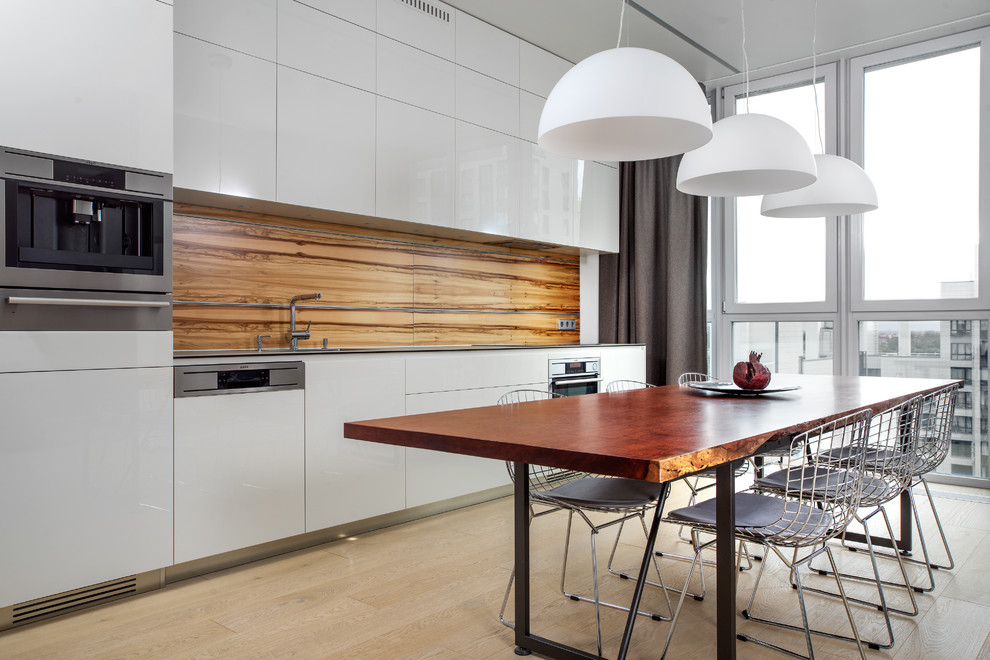 This is an example of a mid-sized contemporary single-wall eat-in kitchen in Saint Petersburg with an undermount sink, flat-panel cabinets, white cabinets, quartz benchtops, light hardwood floors, no island, brown splashback and stainless steel appliances.