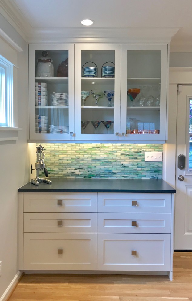 Photo of a small arts and crafts kitchen in Seattle with an undermount sink, shaker cabinets, white cabinets, solid surface benchtops, blue splashback, glass tile splashback, stainless steel appliances, light hardwood floors, yellow floor and grey benchtop.