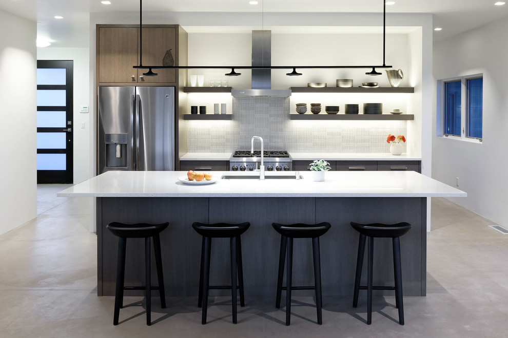 Mid-sized trendy galley concrete floor and gray floor kitchen photo in Denver with an undermount sink, flat-panel cabinets, brown cabinets, glass tile backsplash, stainless steel appliances and an island