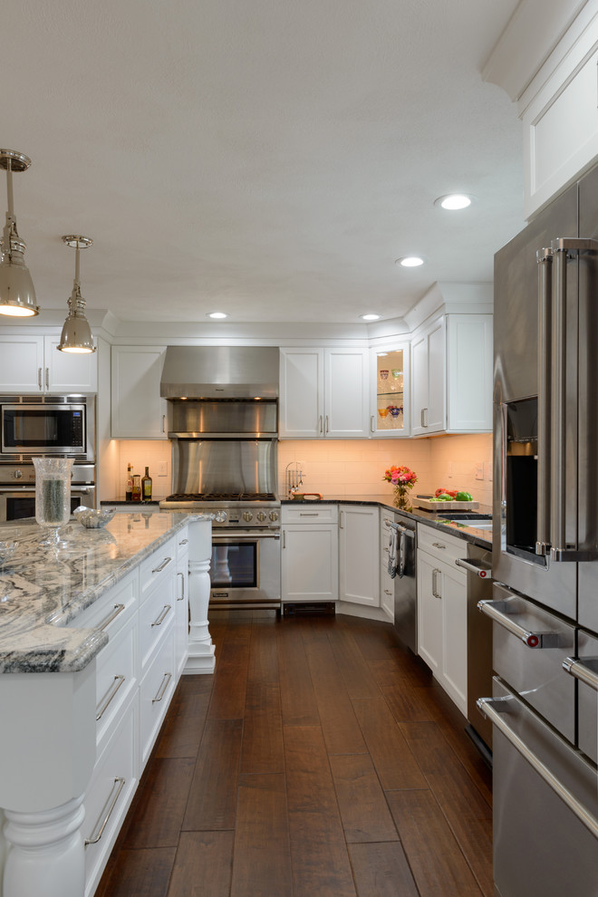 Inspiration for a large traditional l-shaped eat-in kitchen in Boston with an undermount sink, shaker cabinets, white cabinets, granite benchtops, white splashback, porcelain splashback, stainless steel appliances, medium hardwood floors and with island.