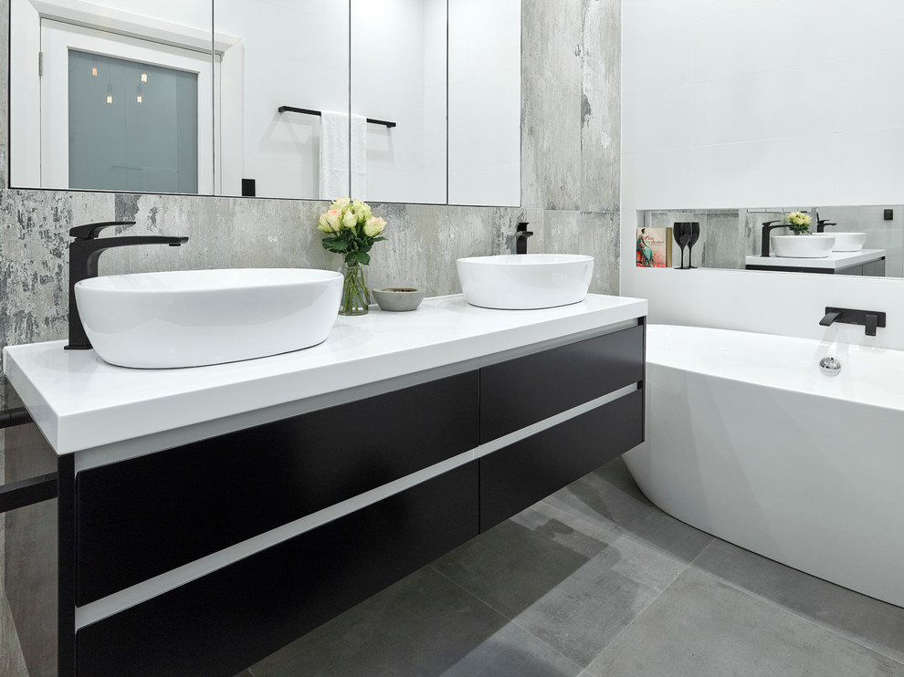 Inspiration for a small industrial bathroom in Adelaide with black cabinets, a freestanding tub, an open shower, a wall-mount toilet, porcelain tile, porcelain floors and a vessel sink.