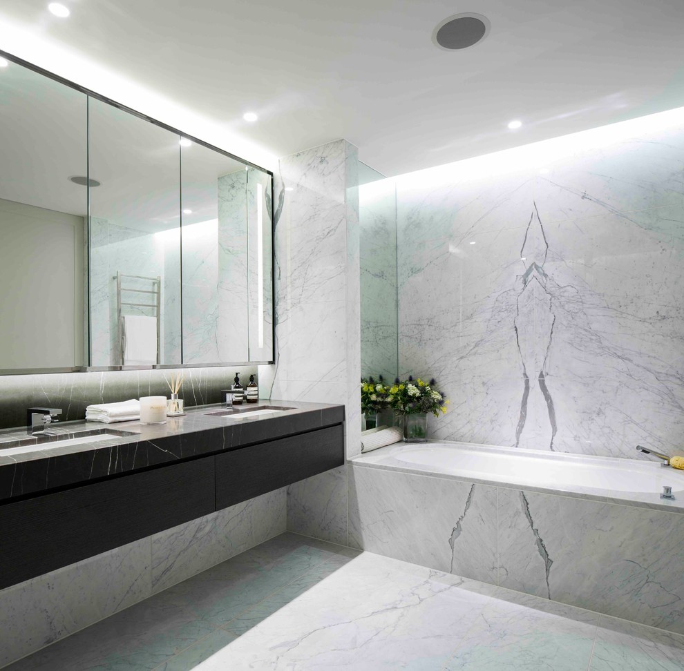 Design ideas for a contemporary bathroom in London with an undermount sink, an undermount tub, gray tile, grey walls, marble floors and marble.