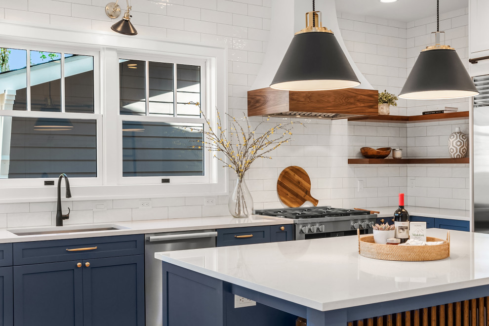 Inspiration for a large transitional u-shaped medium tone wood floor kitchen remodel in Seattle with an undermount sink, shaker cabinets, blue cabinets, quartz countertops, white backsplash, subway tile backsplash, stainless steel appliances, an island and white countertops