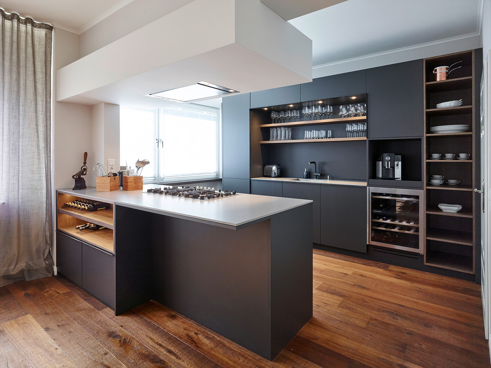 Photo of a mid-sized contemporary galley eat-in kitchen in Dusseldorf with a drop-in sink, flat-panel cabinets, black cabinets, quartzite benchtops, black splashback, stainless steel appliances, dark hardwood floors, multiple islands and brown floor.