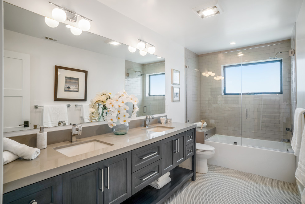 Photo of a transitional 3/4 bathroom in Los Angeles with shaker cabinets, black cabinets, an alcove tub, a shower/bathtub combo, beige tile, subway tile, white walls, mosaic tile floors, an undermount sink, beige floor, a hinged shower door and beige benchtops.