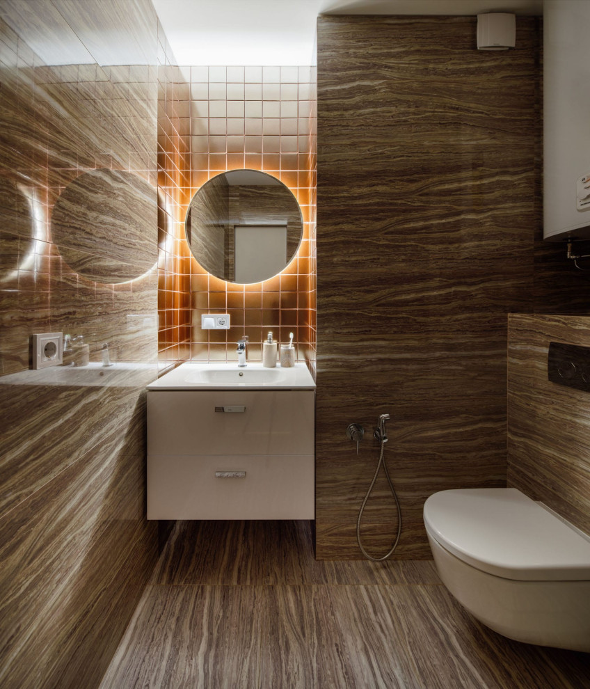 This is an example of a medium sized contemporary cloakroom in Moscow with flat-panel cabinets, white cabinets, a wall mounted toilet, brown tiles, porcelain tiles, brown walls, porcelain flooring, a built-in sink, brown floors, feature lighting and a floating vanity unit.