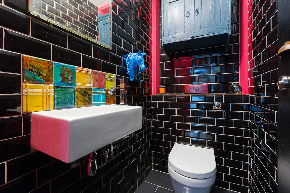 Inspiration for a small eclectic bathroom in London with a wall-mount toilet, black tile, black walls, ceramic floors, grey floor, subway tile and a wall-mount sink.