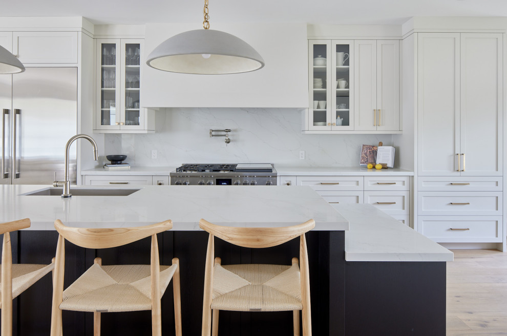 Large transitional single-wall medium tone wood floor and brown floor eat-in kitchen photo with an undermount sink, shaker cabinets, yellow cabinets, quartz countertops, white backsplash, quartz backsplash, stainless steel appliances, an island and white countertops