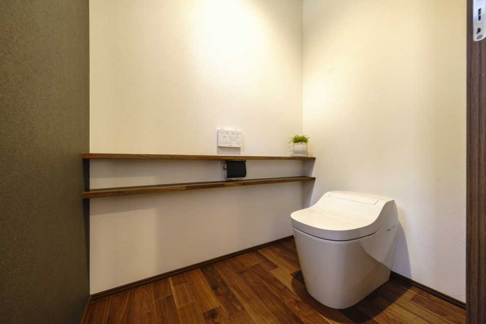 Réalisation d'un WC et toilettes minimaliste de taille moyenne avec WC à poser, un mur blanc, parquet foncé, un sol marron, un plafond en papier peint et du papier peint.
