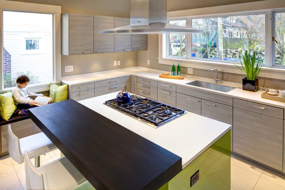 This is an example of a mid-sized modern u-shaped kitchen in Seattle with an undermount sink, flat-panel cabinets, ceramic floors, with island, beige floor, white benchtop, grey cabinets, solid surface benchtops and panelled appliances.