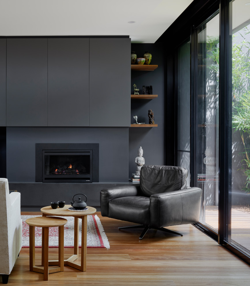 This is an example of a mid-sized modern open concept living room in Melbourne with black walls, medium hardwood floors, a standard fireplace, a plaster fireplace surround and a built-in media wall.