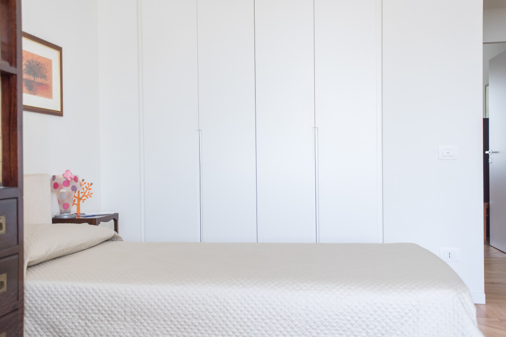 Immagine di una grande cameretta da letto design con pareti bianche, parquet chiaro e pavimento marrone