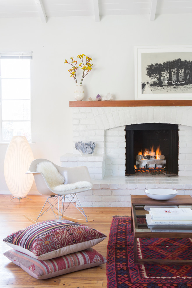 Design ideas for a scandinavian living room in Los Angeles with white walls, light hardwood floors and a standard fireplace.
