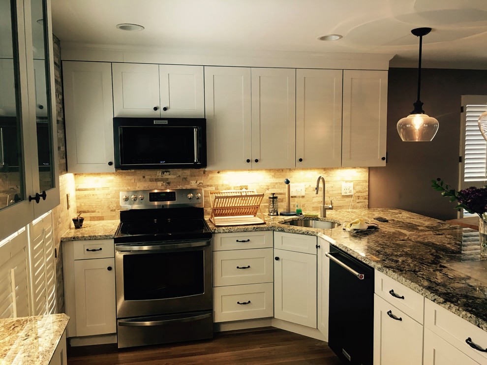 Example of a mid-sized transitional l-shaped medium tone wood floor and brown floor open concept kitchen design in DC Metro with an undermount sink, shaker cabinets, white cabinets, granite countertops, beige backsplash, stone tile backsplash, stainless steel appliances and a peninsula