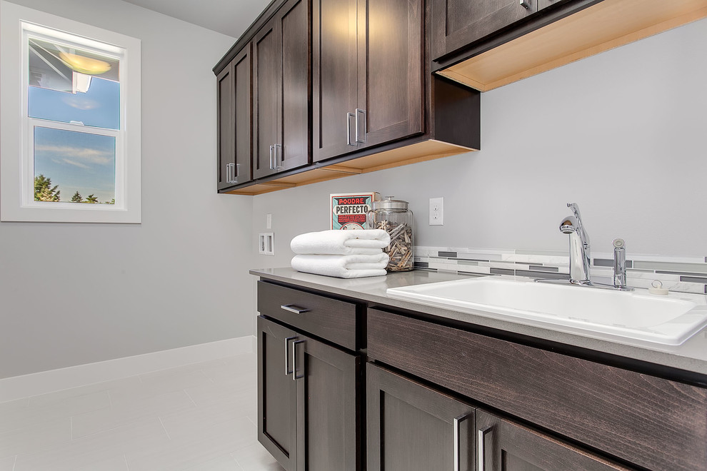 This is an example of a mid-sized transitional single-wall dedicated laundry room in Seattle with an utility sink, recessed-panel cabinets, medium wood cabinets, quartzite benchtops, grey walls and a side-by-side washer and dryer.