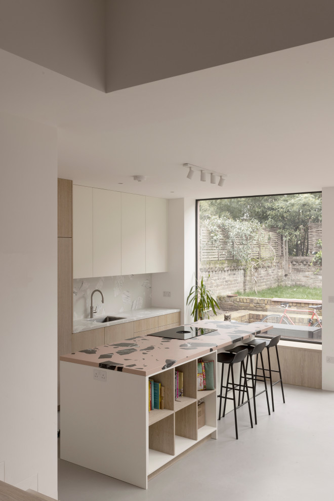 Inspiration for a mid-sized contemporary l-shaped open plan kitchen in London with an integrated sink, flat-panel cabinets, light wood cabinets, terrazzo benchtops, grey splashback, panelled appliances, concrete floors, with island, grey floor and multi-coloured benchtop.
